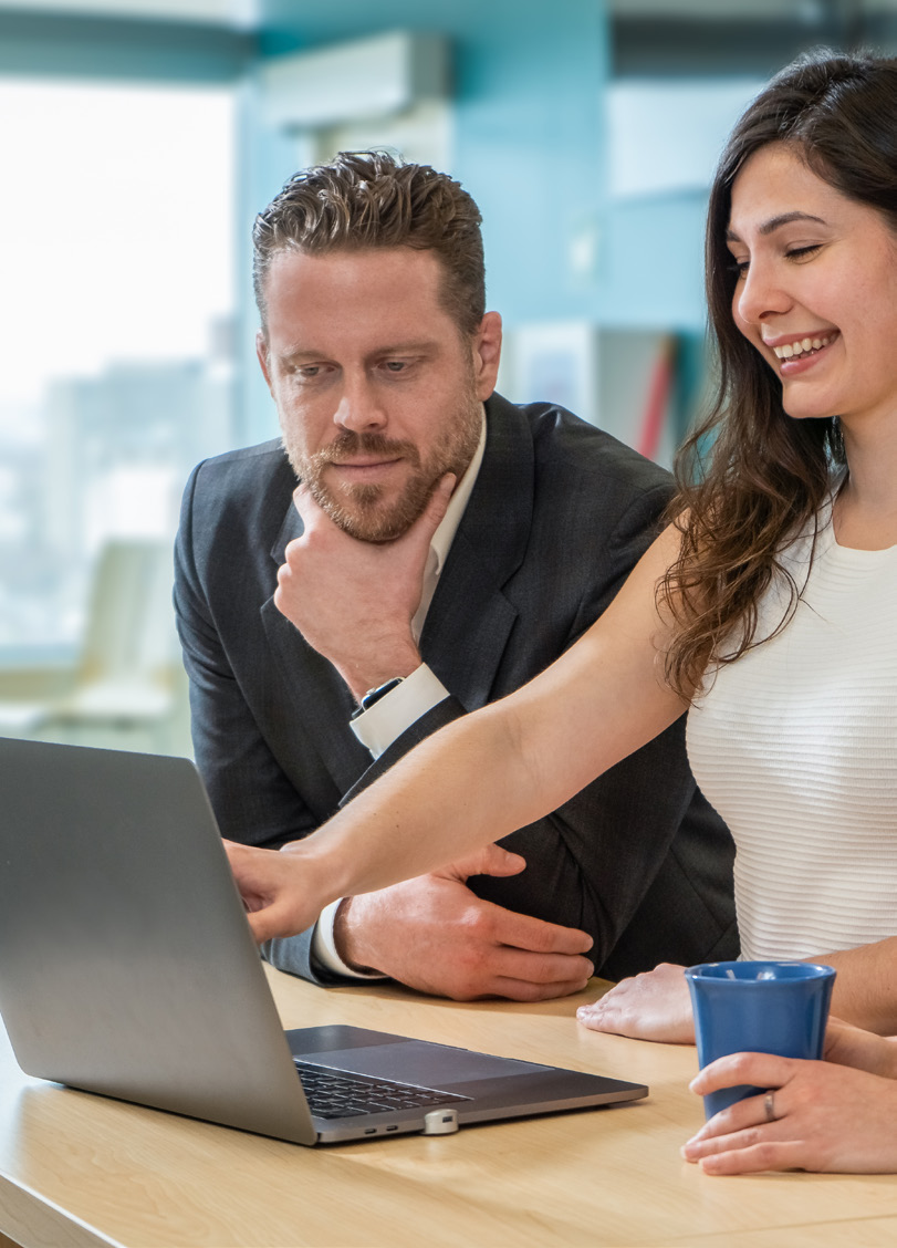 An man and a woman standing at a laptop