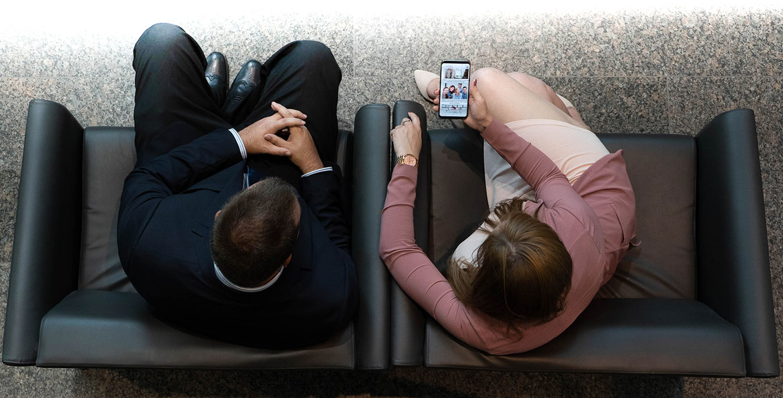 Deux personnes assises sur un fauteuil consultant sur un téléphone