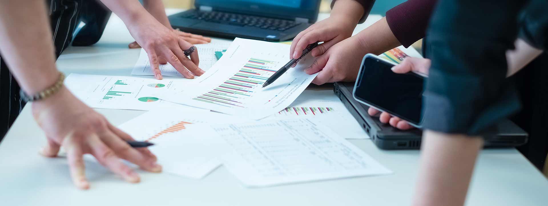 Hands of various persons pointing at documents on a table
