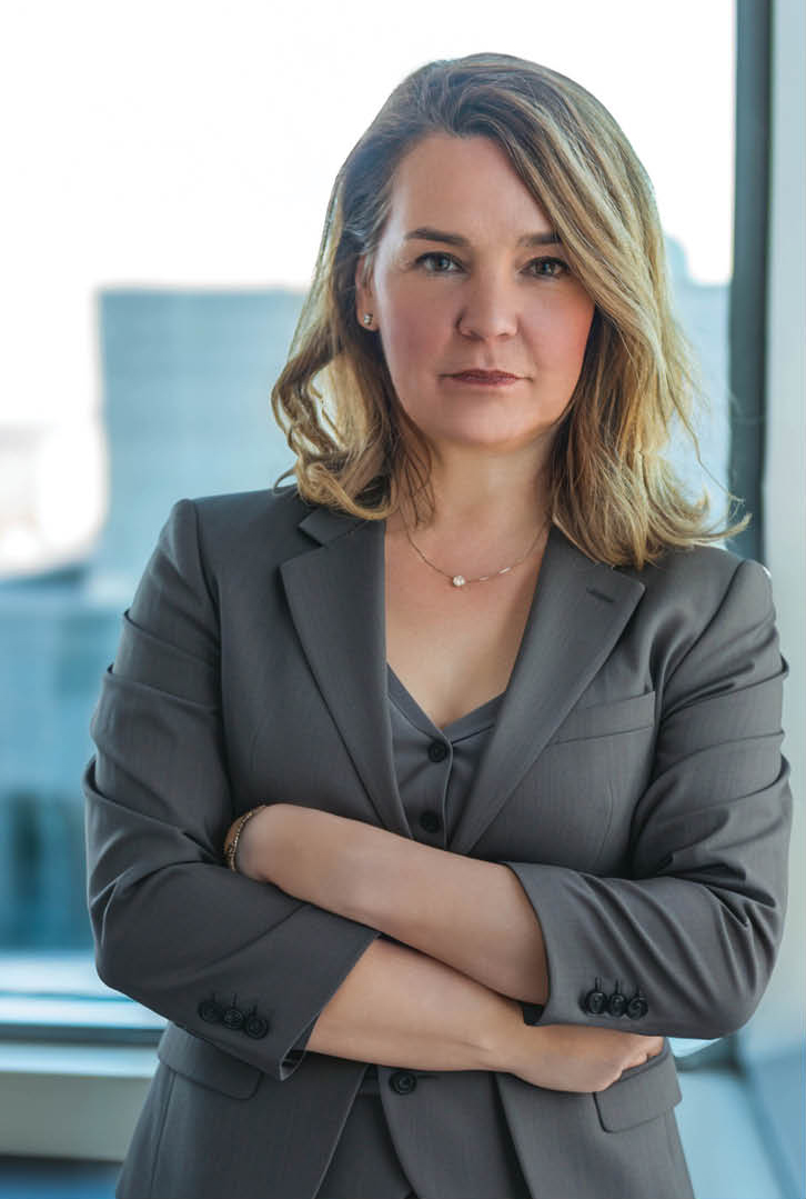 Information Commissioner of Canada with a neutral expression, leaning on a window at the office.